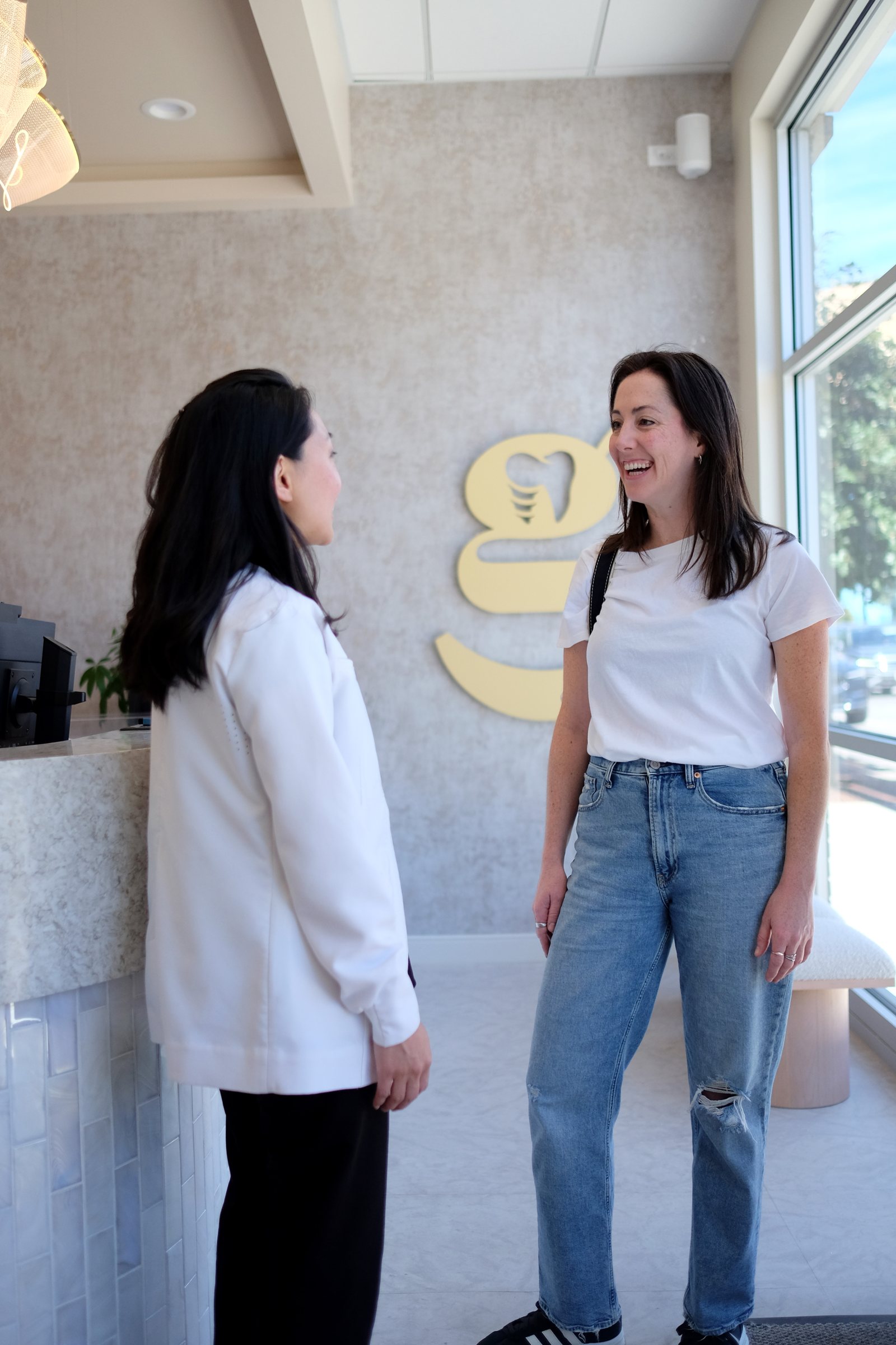 A patient laughing with Dr. Erin Cho at reception, under the gold Regen mark